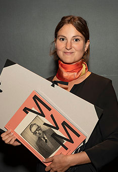 Anna Deér, die Gewinnerin des Preis der Max von Moos-Stiftung, hält ihre Urkunde und eine Publikation über Max von Moos.