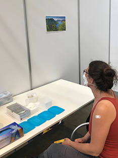 Frau im Corona Impfzentrum betrachtet eine Naturfotografie