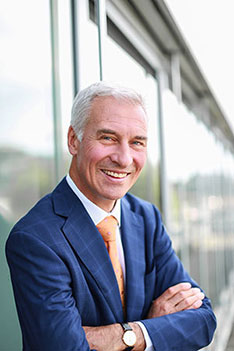 Portrait des lächelnden Peter Fischer vor einer Glasfront