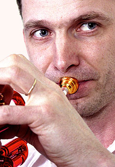 Portrait von dem in eine Trompete blasenden Marco Blaauw, er ist Dozent für Trompete und Brass