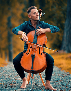 Jodok Vuille, barfüssig, spielt Cello auf einem Schotterweg in herbstlicher Waldlandschaft. Bild ZVG Jodok Vuille