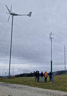 Eine Gruppe Menschen steht in einem Windpark mit kleinen Windrädern