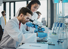 Frau und Mann an einem Mikroskop in einem Labor