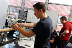 In Networking Lab stellt ein Student eine Verbindung von einem Router zu seinem Laptop her.