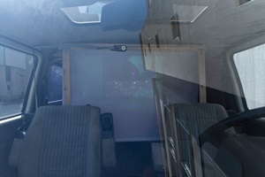 Ein Blick ins Innere eines VW-Busses, wo eine Leinwand zu sehen ist.
