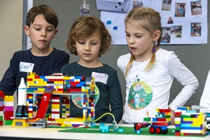 Zwei Mädchen und ein Junge präsentieren ihr First Lego League Projekt