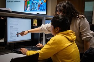 Eine junge Frau zeigt einem Jungen etwas am Computer