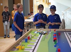 Drei Kinder stehen vor einem Tisch mit Roboterlabyrint