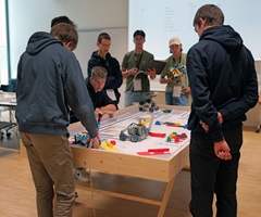 Eine Gruppe junger Menschen stehen an einem Tisch mit Roboterlabyrint