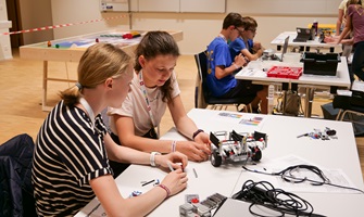 Zwei Mädchen sitzen an einem Tisch und arbeiten an einem Lego-Roboter