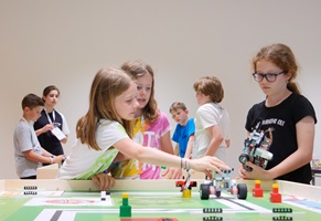 Drei Mädchen stehen um einen Arbeitstisch mit einem Roboterlabyrint