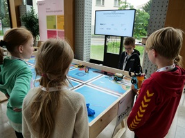 Vier Kinder stehen um einen Arbeitstisch mit einem Roboterlabyrint