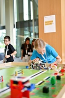 Ein Mädchen steht an einem Tisch und arbeitet an einem Lego-Roboter