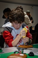 Ein Junge verziert mit gelber Zuckerglasur einen Lebkuchen