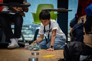 Ein Junge arbeitet am Boden mit einem Lego-Roboter