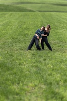 Zwei junge Menschen tanzen in der Natur auf einer Wiese. 