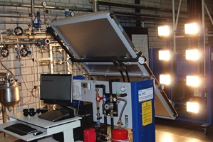 (1)	Das Bild zeigt den Betrieb des Kollektors in schiefer Lage. Im Vordergrund ist der Computer zu sehen auf dem die Betriebsparameter mit Hilfe einer Software aufgezeichnet werden. Im Hintergrund ist die Lichtquelle ersichtlich.