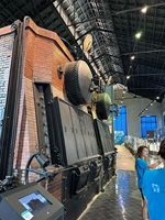 Historische Industrieanlage mit großem Kessel und technischen Maschinen in einer Ausstellungshalle.