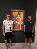 Zwei Besucher stehen neben einem farbenfrohen Gemälde eines Mädchens in einer Kunstausstellung.