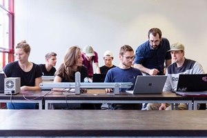 Studierende arbeiten gemeinsam an einer technischen Versuchsanlage mit Laptop und Messgerät