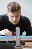 Student adjusts a small model car on a technical testing setup