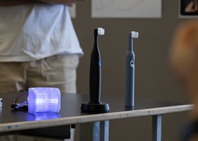 Electric toothbrushes and glowing mouthpiece prototypes displayed on a table in a seminar