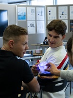 Students examine a glowing mouthpiece model during a design presentation