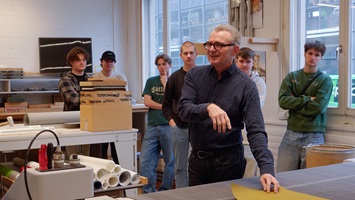 Instructor explains materials and surface finishing to students in a workshop