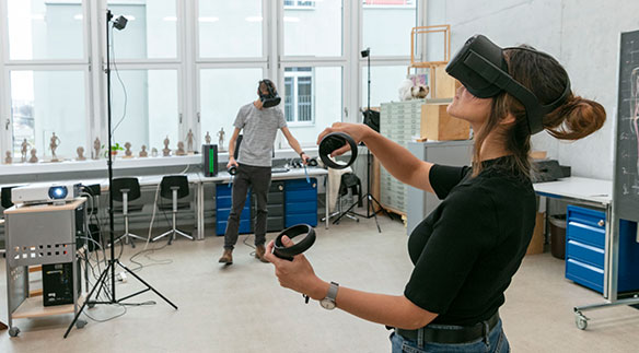 Eine Studentin mit VR Brille und Joysticks