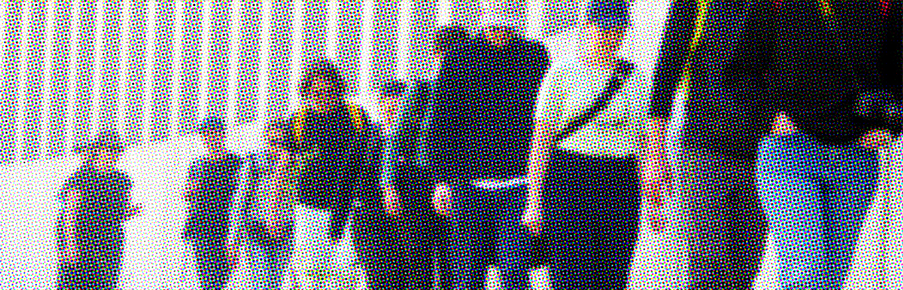 Menschen gehen hintereinander einer hohen Mauer entlang