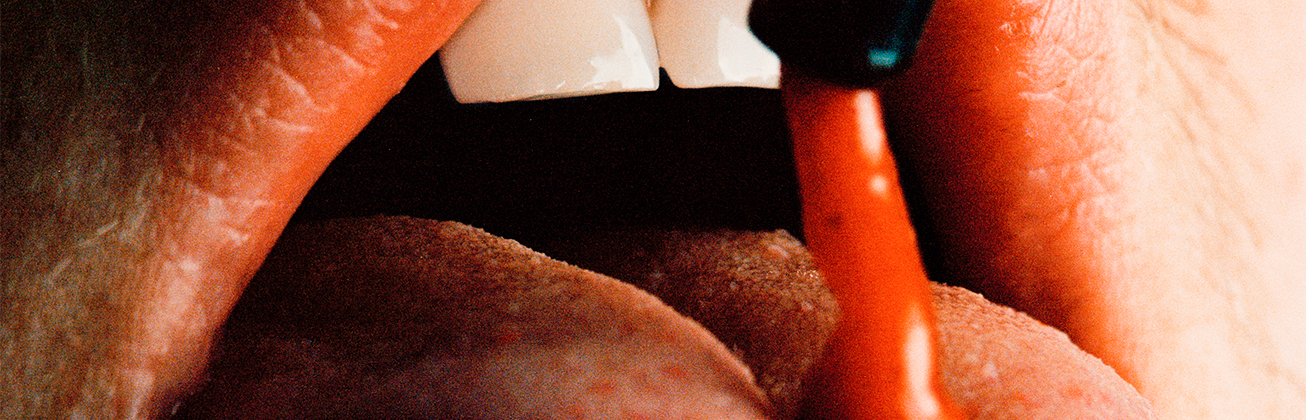 Eine rote Flüssigkeit tropft auf eine Zunge