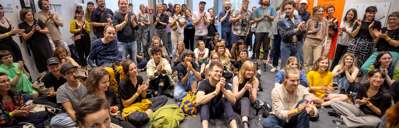 Viele Menschen sitzen auf dem Boden und klatschen