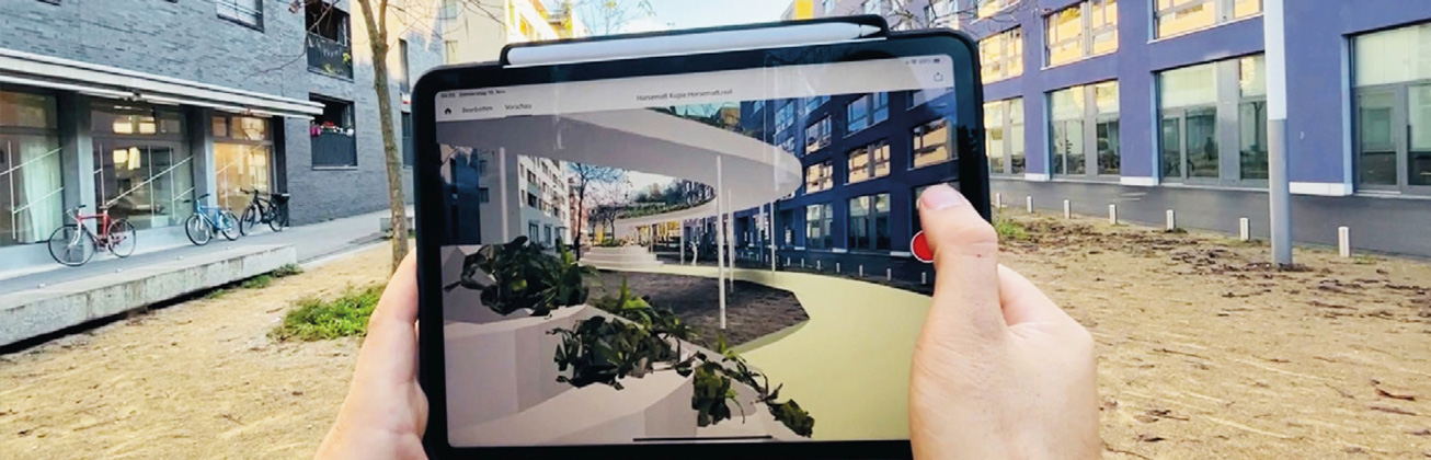 Jemand hält ein Ipad vor zwei Gebäuden, die als Aumented Reality auf den Bildschirm übertragt werden