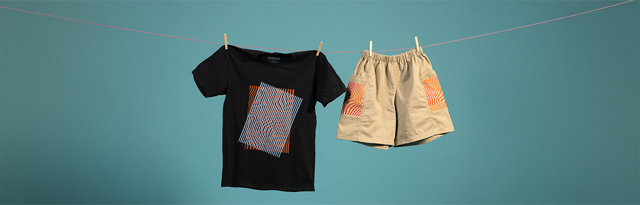     Schwarzes T-Shirt mit orange-blauem grafischem Muster und beige Shorts mit orange-weiss gemusterten Taschen, mit Wäscheklammern an einer Leine vor türkisfarbenem Hintergrund befestigt.