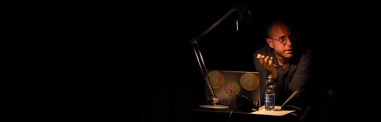 Ein Mann, der an einem Tisch im Dunklen arbeitet und nur der Tisch und er sind beleuchtet