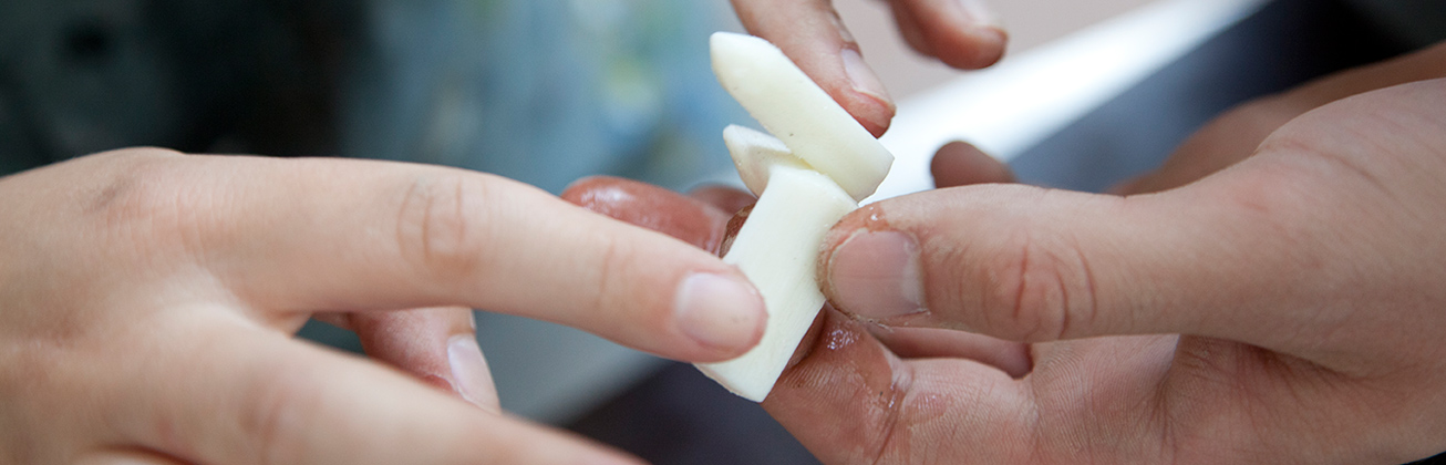 Hände, die ein Kunststoff-Stück halten