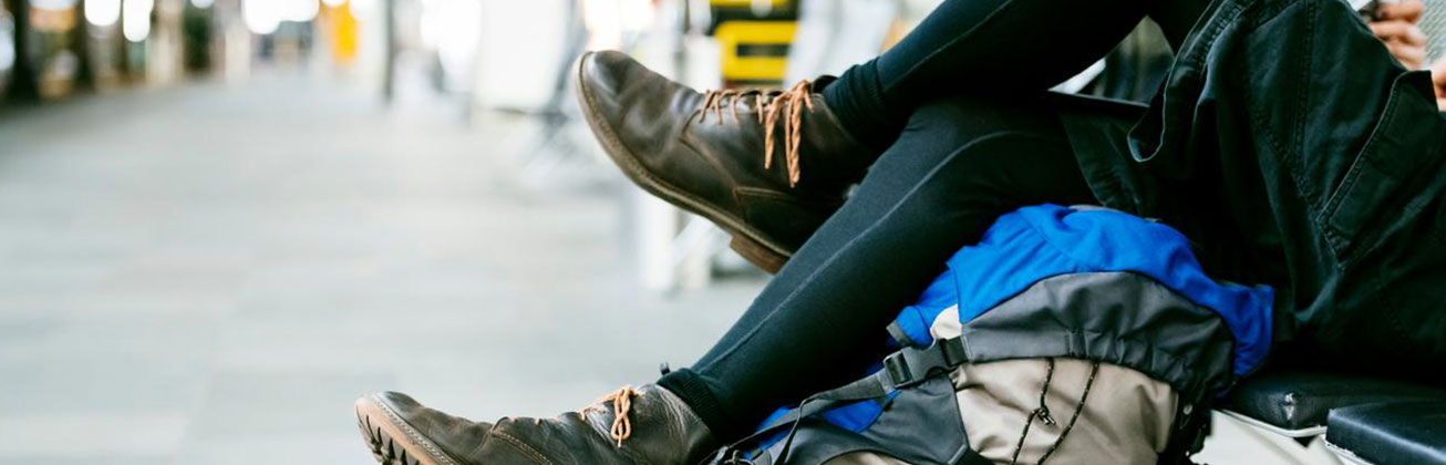 Person sitzt am Bahnhof mit ihrem Rucksack