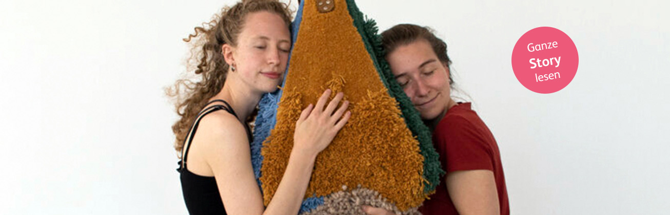 Zwei Studentinnen mit geschlossenen Augen lehnen entspannt an ein großes, buntes Kissen, die eine von links, die andere von rechts