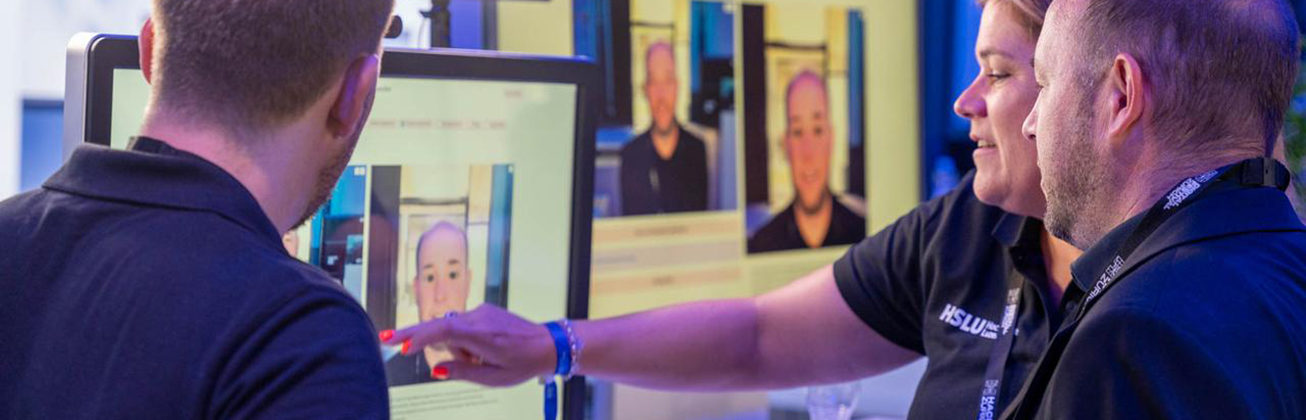 Drei Personen an einem Bildschirm auf einer Messe