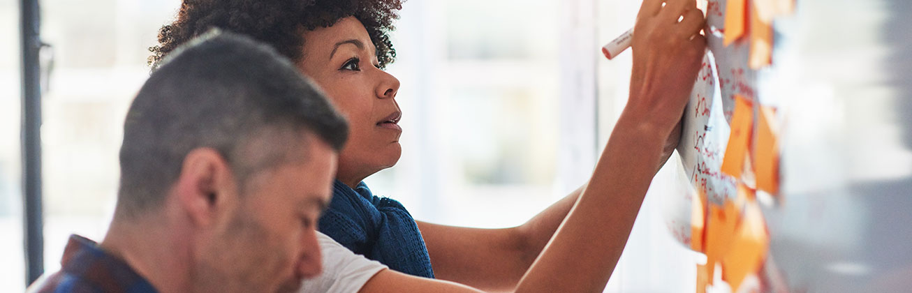 Eine Frau und ein Mann vor einem Whiteboard