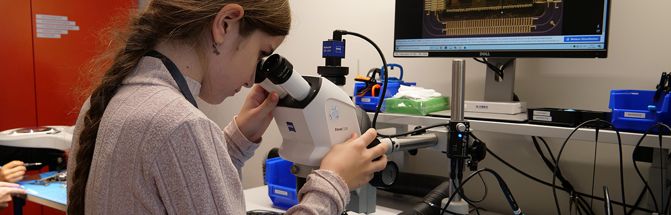 Maedchen schaut durch Mikroskop