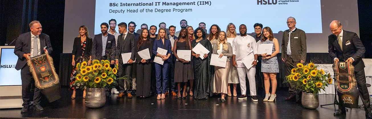 Studierende auf einer Bühne mit ihrem Abschlusszeugnis in der Hand