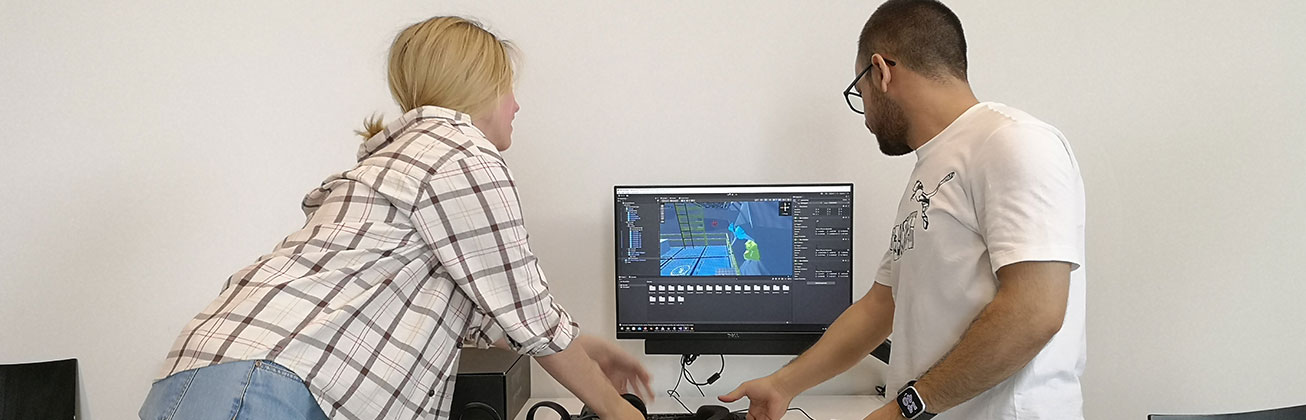 Eine Studentin und ein Student schauen zusammen auf einen Bildschirm, wo eine grafische Darstellung zu sehen ist