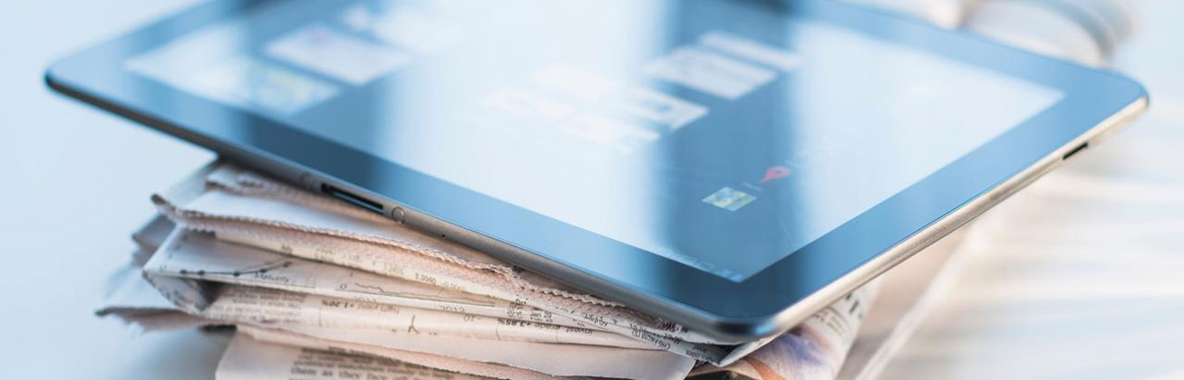 Tablet auf einem Stapel Zeitungen