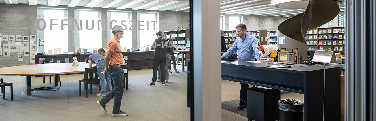Menschen stehen in der Bibliothek, am Eingang