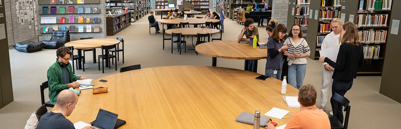 Menschen arbeiten an einem grossen runden Tisch in der Bibliothek