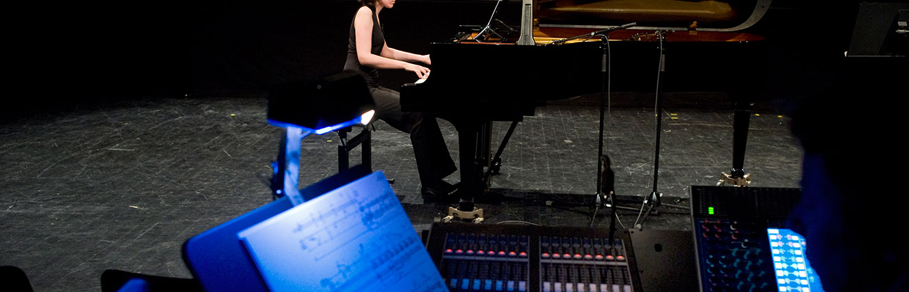 Mischpult im Vordergrund, im Hintergrund eine Pianistin