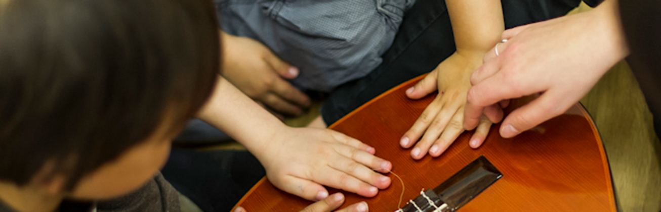 Kinderhände auf einer Gitarre