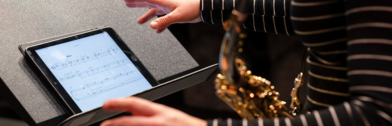 Hände einer Saxofonistin, welche an einem Tablet die Seite umblättert. Bild HSLU/Priska Ketterer