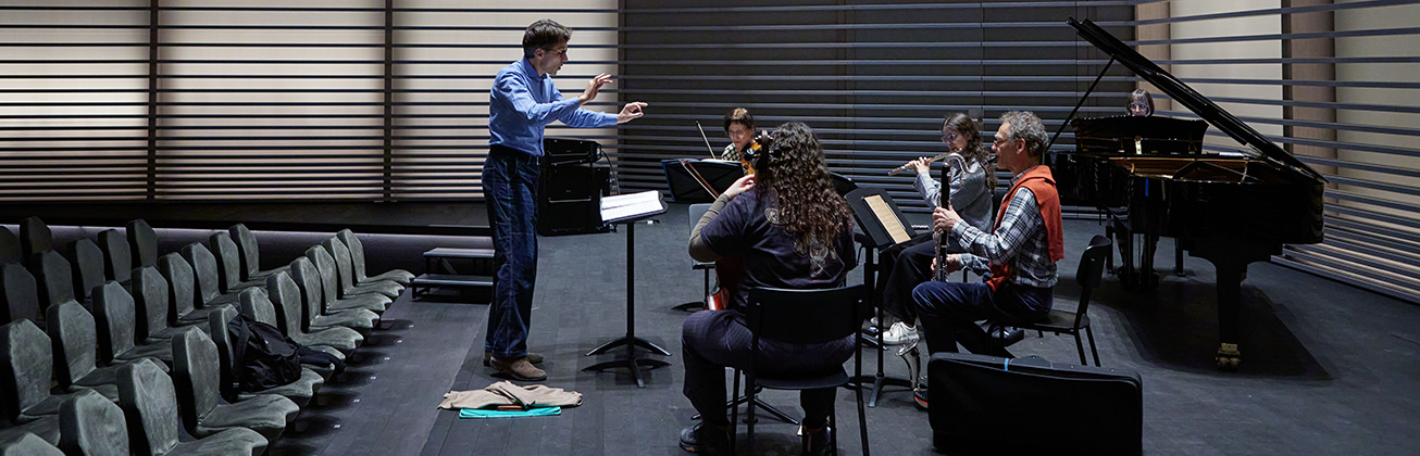 Ein Quartett probt gemeinsam auf der Bühne und wird von einem Dozent dirigiert 